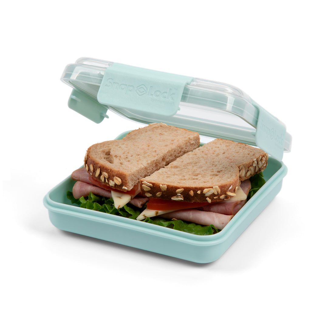 light blue plastic food storage container lunch box with open lid revealing a sandwich with tomato, pepper jack cheese, ham, and lettuce