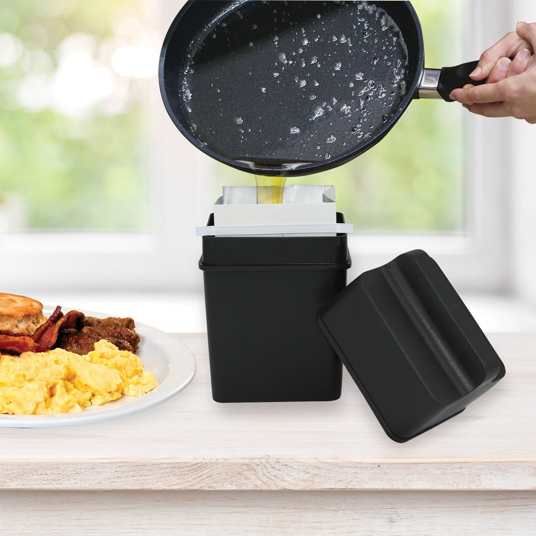 Pouring warm bacon grease from a skillet into a Range Kleen Fat Trapper grease disposal container on a kitchen counter
