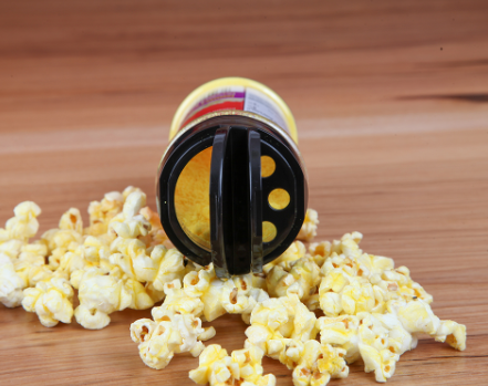 sideways bottle of sweet caramel popcorn seasoning on top of wood kitchen counter with flavored popcorn